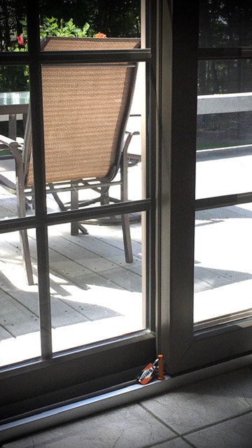 Orange Bolo Stick sliding door stopper set in the track beside a closed patio door